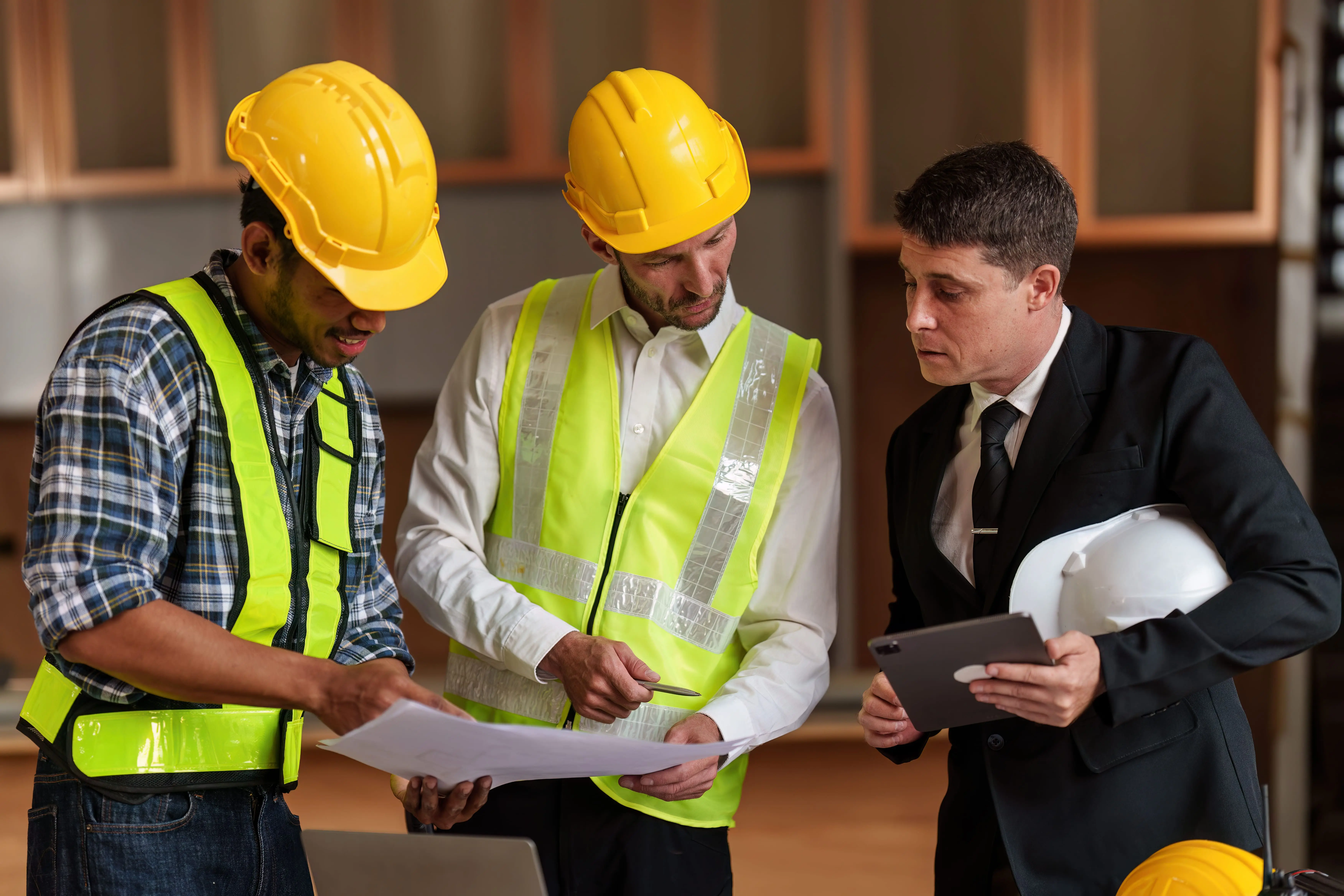 Three safety workers engaged in a discussion while reviewing an inspection checklist