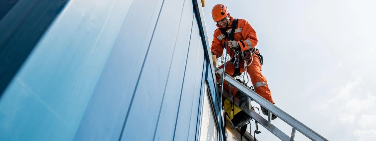 A worker on a skyscraper wearing safety harnesses while working at a considerable height