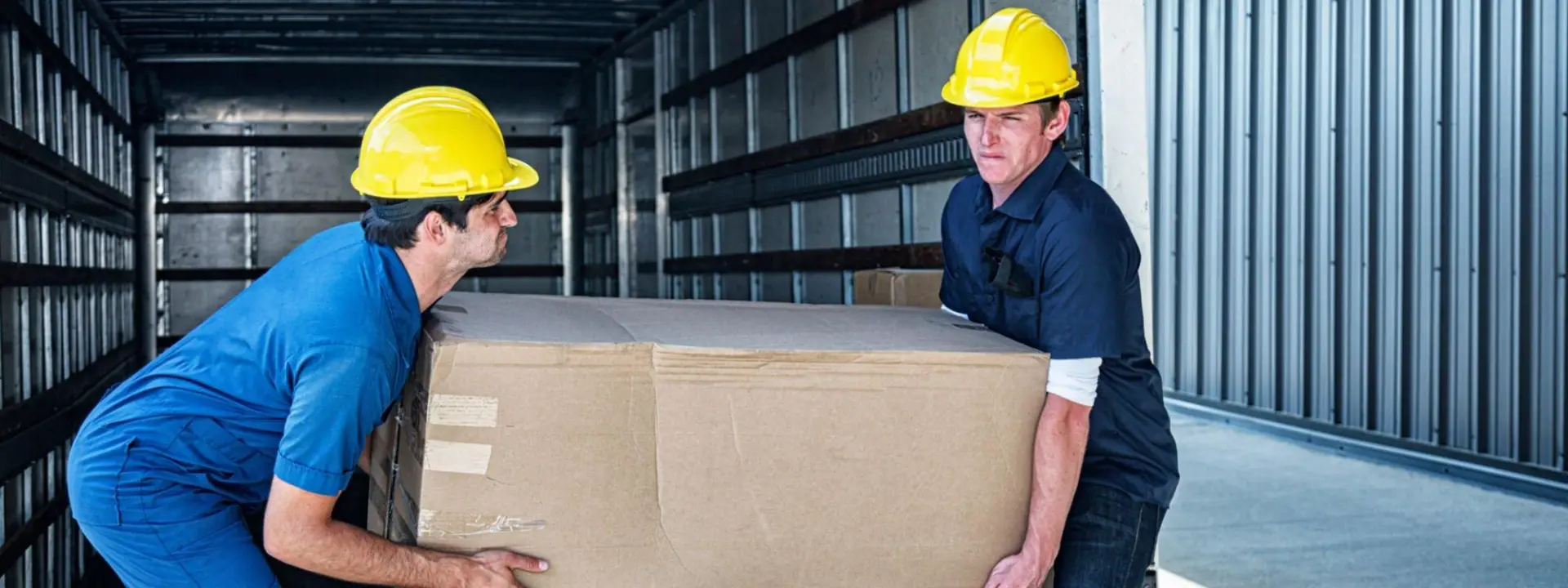 Two employees working together to lift a heavy box