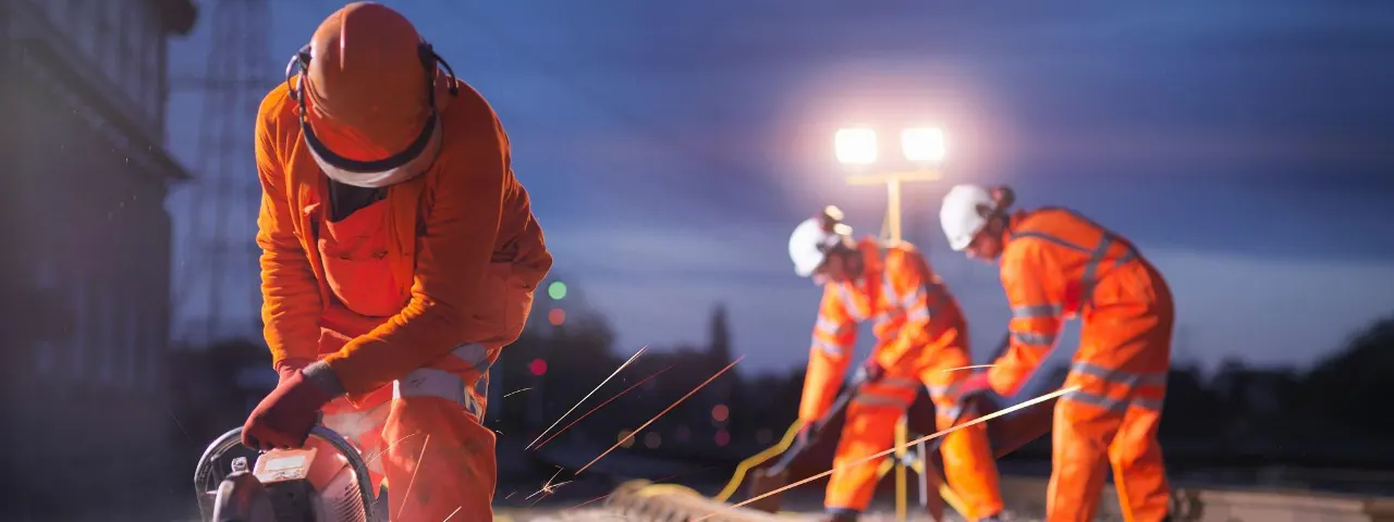 Railway maintenance workers using a grinder on the track during night